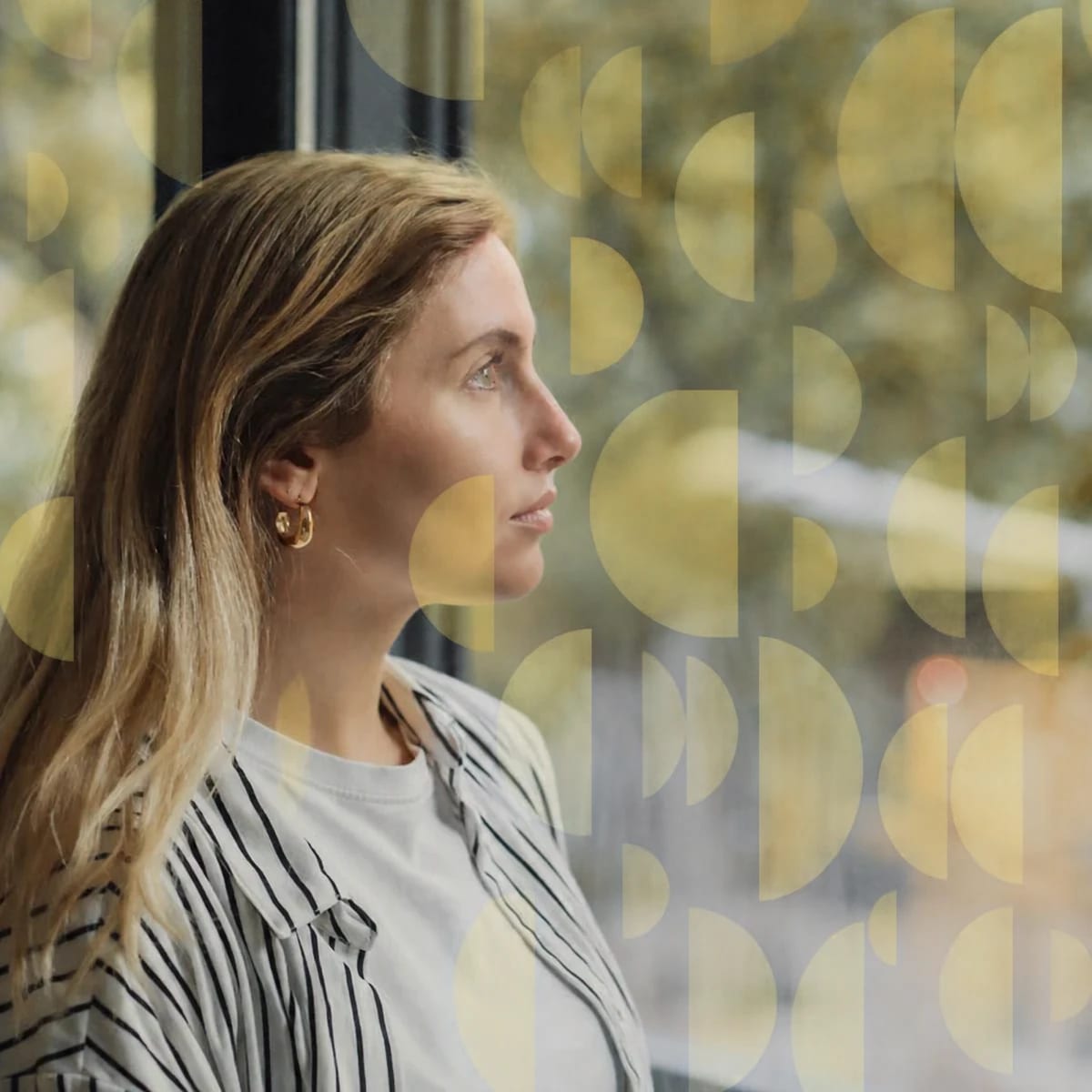 A woman looks out a window in quiet reflection.